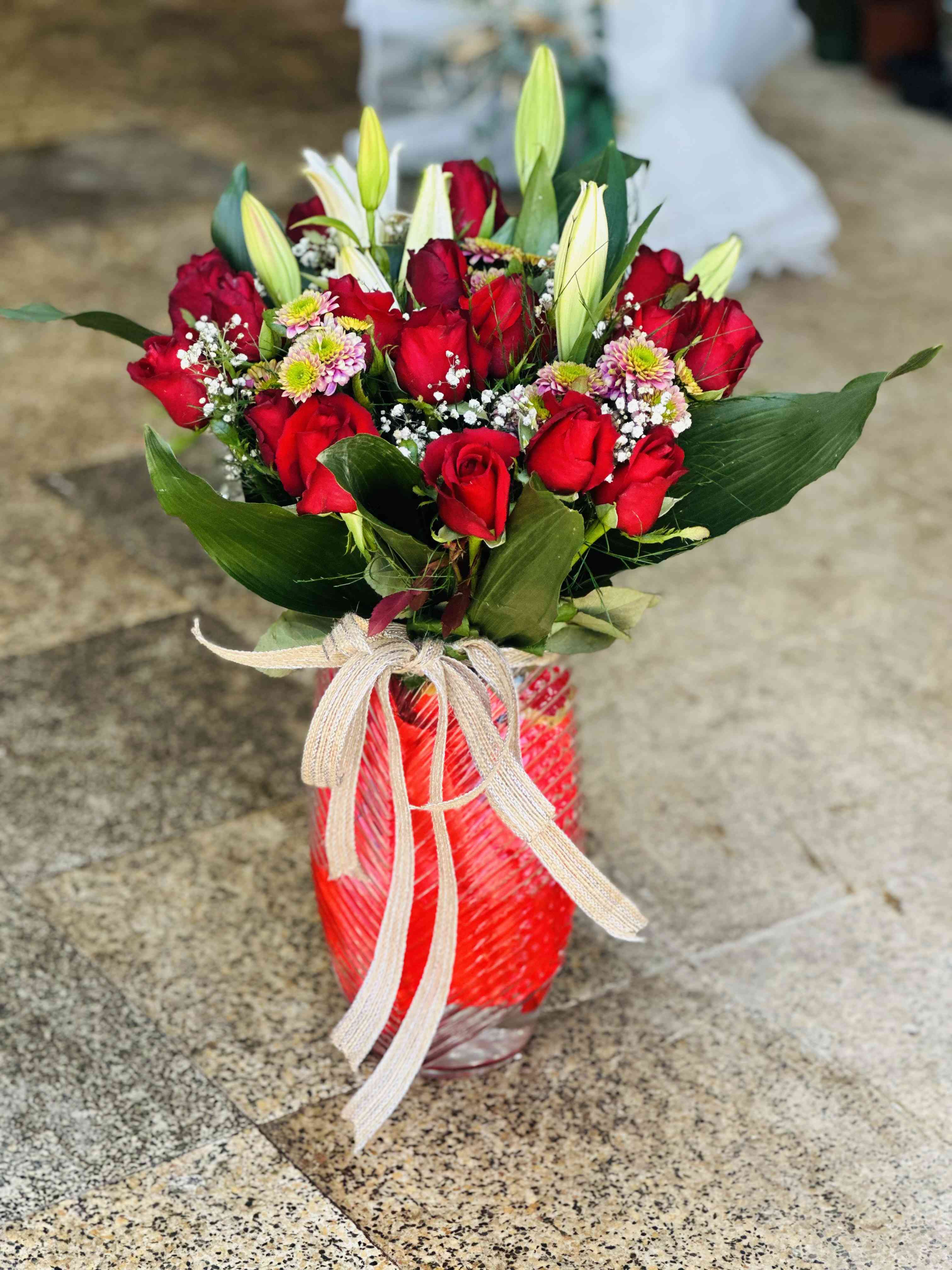 Cam vazo içerisinde kırmızı güller ve lilyumlar