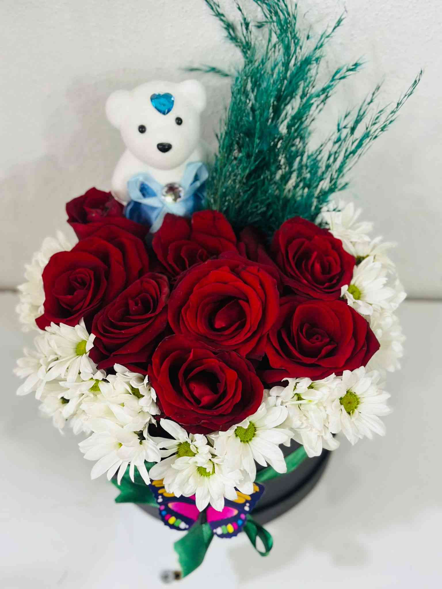 Kutuda kırmızı güller ve papatyalar.